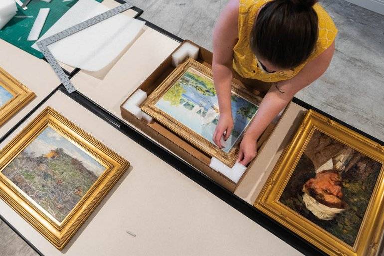 woman packing framed artwork into boxes
